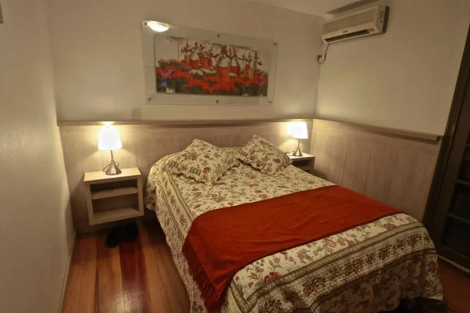 Suíte 1 da casa principal com cama de casal e janela para a vegetação